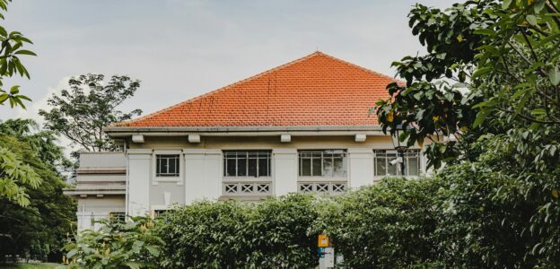 a white house with a red roof surrounded by trees