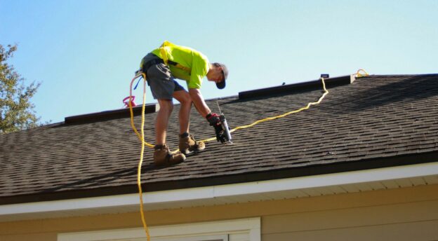 a man working on a roof with a power drill